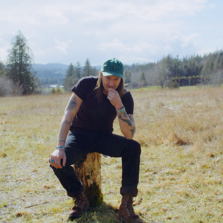 Man in filed wearing Black selvedge denim jeans made in USA with Native American Ginew Leather Patch 
